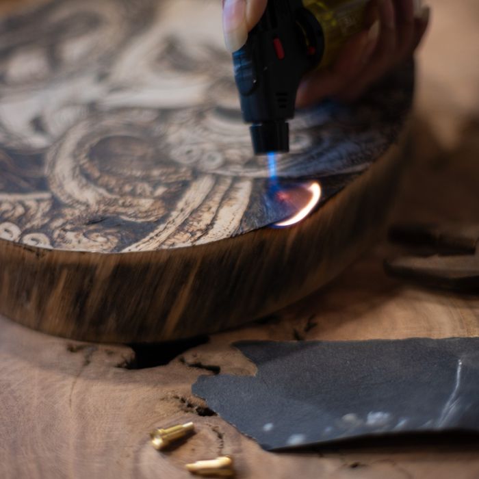 A torch flame scorching the live edge of a thick round slab