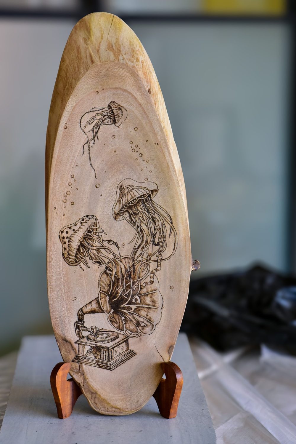 Submerged Song — three jellyfish rising like music from a gramophone, burned on a long oval slab